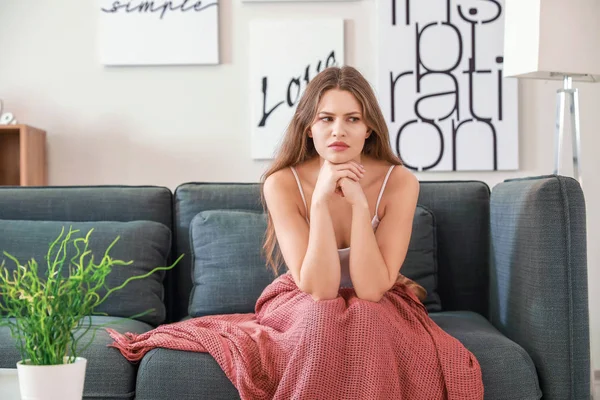 Depressed young woman sitting on sofa at home — Stock Photo, Image