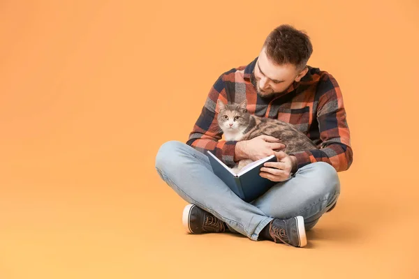 Человек с милой книгой для чтения кошек на цветном фоне — стоковое фото
