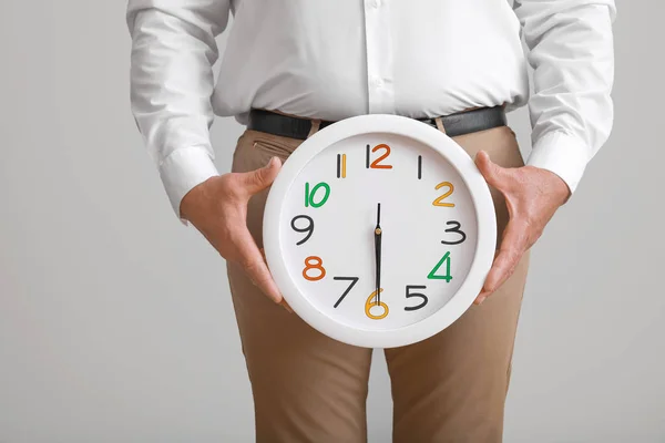 Mature man with clock on light background. Urology concept — Stock Image Mature man with clock on light background. Urology concept Royalty Free Stock Photos