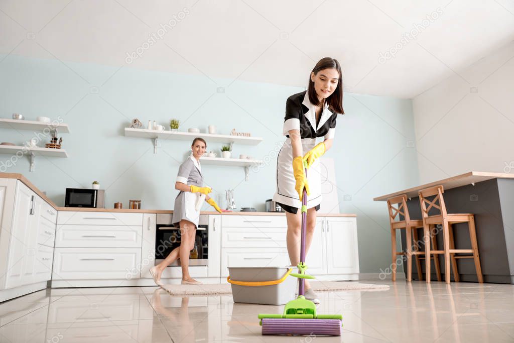 Beautiful young chambermaids cleaning kitchen