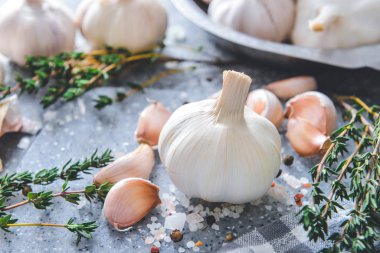 Baharatlı taze sarımsak ve gri arka planda bitkiler.