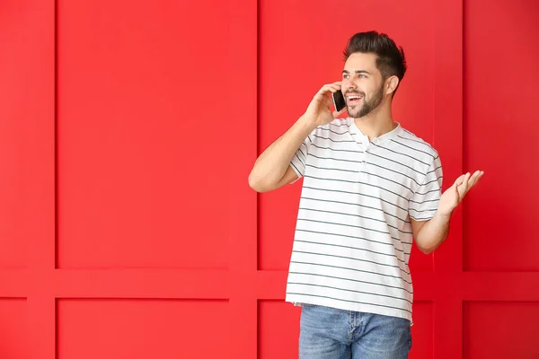 Happy jongeman praten door mobiele telefoon op kleur achtergrond — Stockfoto