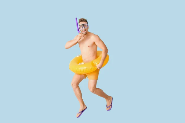 Jumping jovem com anel inflável, máscara de snorkeling e tubo no fundo de cor — Fotografia de Stock