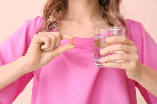 Young woman with fish oil on color background, closeup — Stock Photo, Image