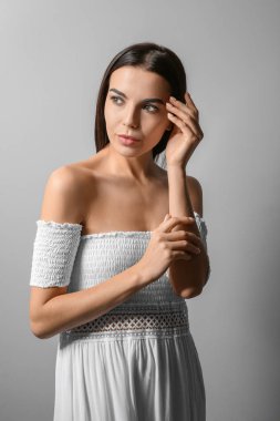 Gri arka planda güzel, modaya uygun genç bir kadın.