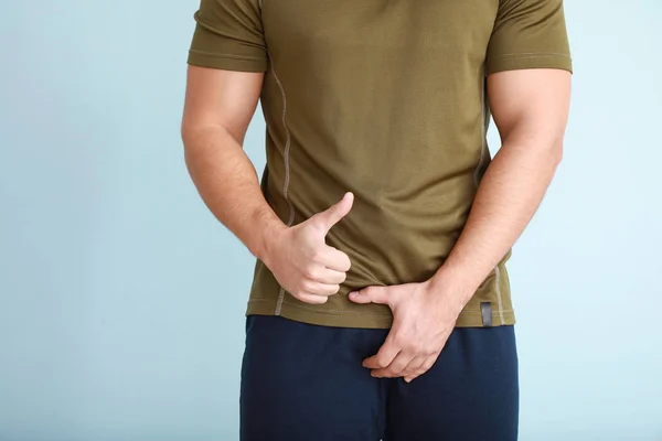 Jongeman met gezond urogenitaal systeem met duim-up op lichte achtergrond — Stockfoto