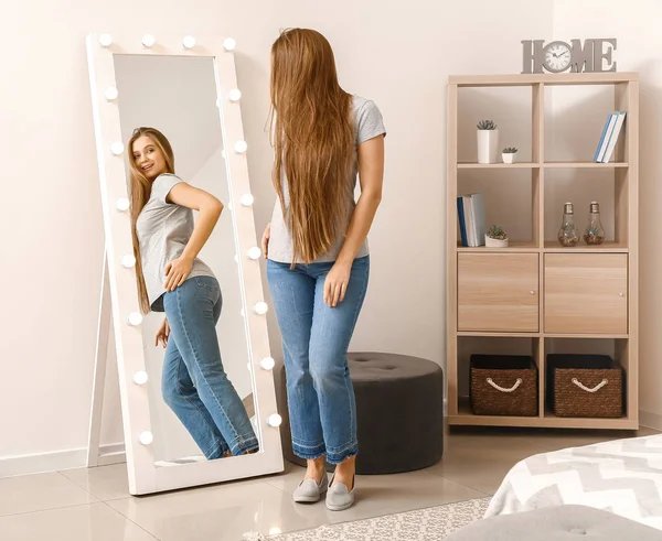 Hermosa joven mujer mirando su reflejo en el espejo — Foto de Stock