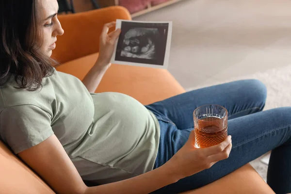 妊娠中の若い女性は自宅でアルコールを飲む — ストック写真