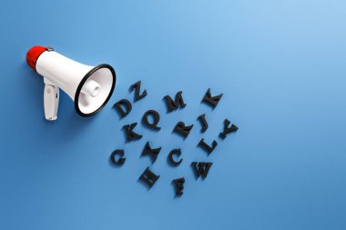 Megaphone with letters on color background clipart