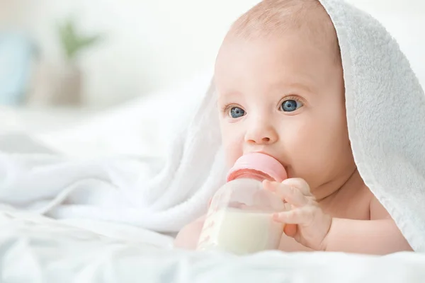 Портрет милої маленької дитини, що п'є молоко з пляшки на ліжку — стокове фото