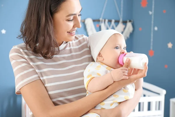 Az anya otthon cumisüvegből tejjel eteti a babát. — Stock Fotó