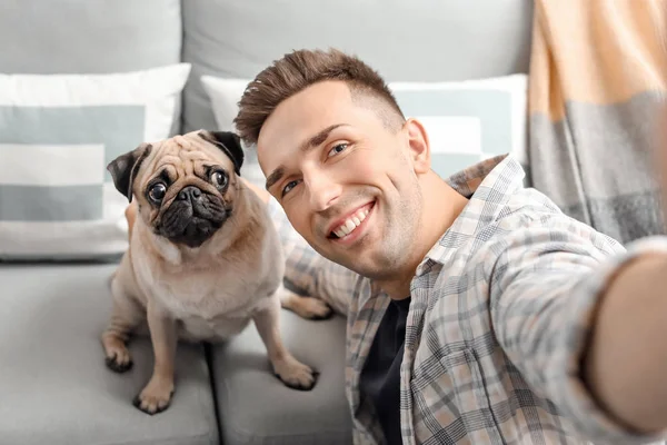 Handsome man taking selfie with cute pug dog at home — Stock Photo, Image