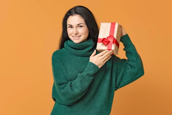Beautiful young woman with gift on color background — Stock Photo, Image