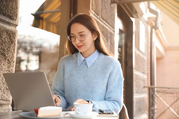 Young woman with laptop in outdoor cafe — 스톡 사진