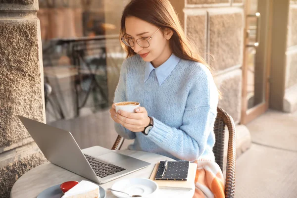 Young woman with laptop drinking coffee in outdoor cafe — 스톡 사진