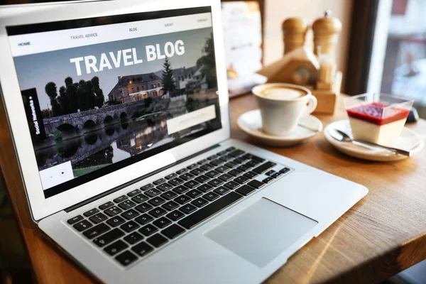 Ноутбук с открытой страницей туристического блога на столе в кафе — стоковое фото