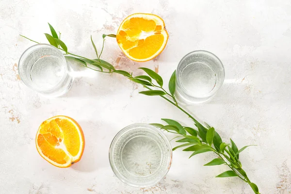 Bicchieri di acqua pulita e arancione su sfondo chiaro — Foto Stock