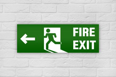 Tuğla duvarda acil çıkış işareti var.