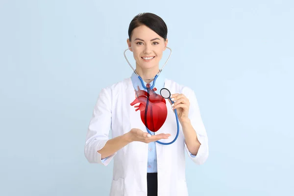 Female cardiologist with drawn heart and stethoscope on color background — Stock Photo, Image