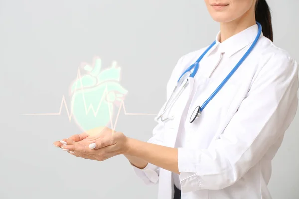 Cardiologista feminino segurando coração desenhado em fundo claro — Fotografia de Stock