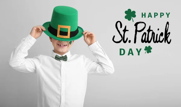 Grappig jongetje en tekst Gelukkige St. Patrick 's Day op lichte achtergrond — Stockfoto