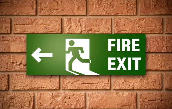 Sign of emergency fire exit on brick wall — Stock Photo, Image