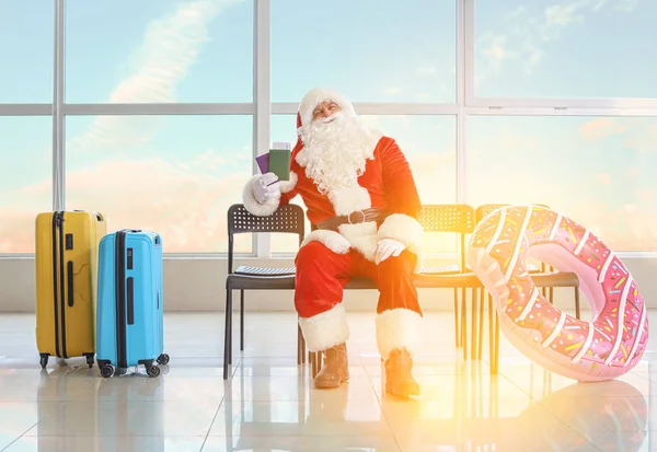 Santa Claus se zavazadly čeká na svůj let na letišti. Koncept dovolené — Stock fotografie