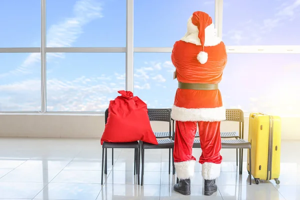 Санта Клаус з багажем чекає на свій рейс в аеропорту. Концепція відпустки — стокове фото