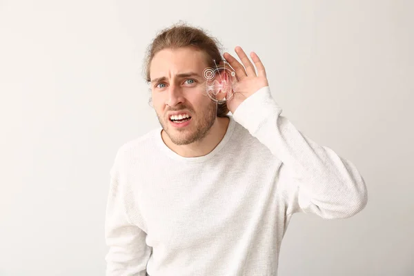 Young man with hearing problem on light background — Stock Photo, Image