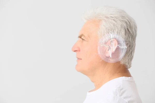 Handsome mature man with hearing problem on light background — Stock Photo, Image