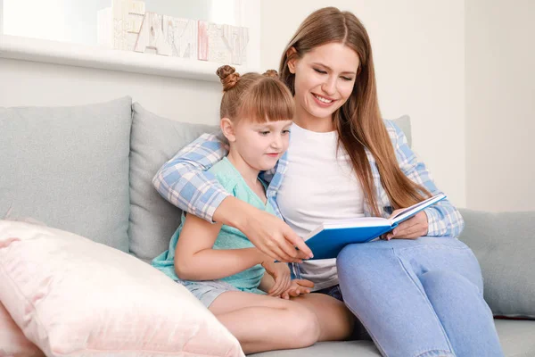 Mooie jonge vrouw en haar dochtertje lezen boek thuis — Stockfoto