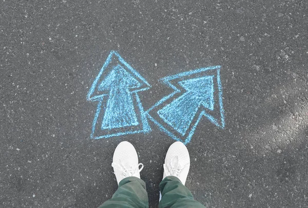 Person standing on road with arrows pointing in different directions. Concept of choice