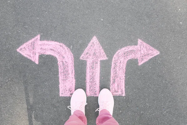 Person standing on road with arrows pointing in different directions. Concept of choice