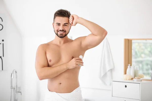 Przystojny, młody człowiek, przy użyciu dezodorantu w łazience — Zdjęcie stockowe