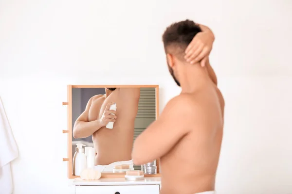 Bello giovane uomo che utilizza il deodorante in bagno — Foto Stock