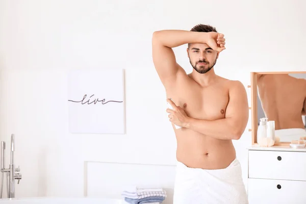 Joven guapo usando desodorante en el baño — Foto de Stock