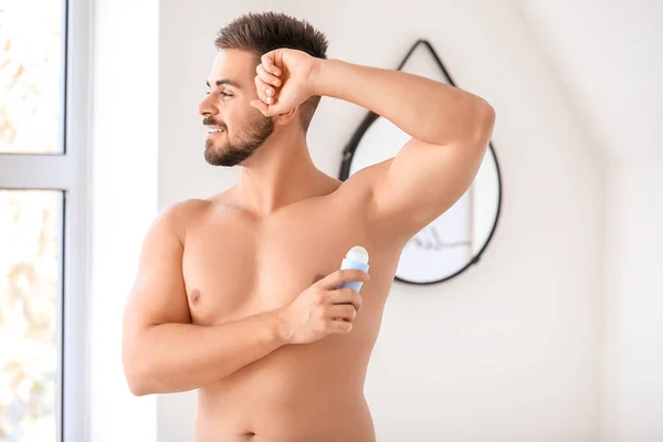 Handsome young man using deodorant in bathroom — Stock Photo, Image