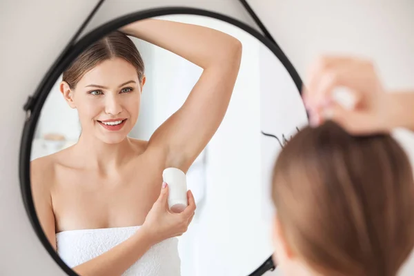 Beautiful young woman using deodorant in bathroom — Stockfoto