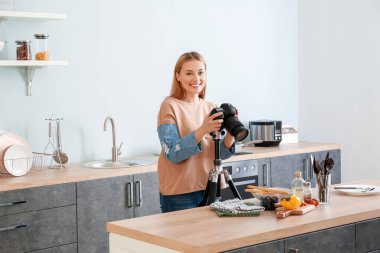 Genç fotoğrafçı mutfakta sebze salatası fotoğrafı çekiyor.