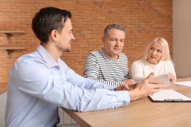 Erkek emlakçı içeride olgun bir çiftle çalışıyor.