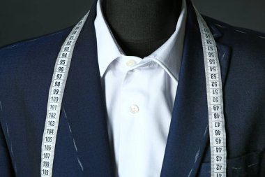 Terzinin bitmemiş giysileri ve koyu arkaplanda şerit olan mankeni, yakın plan.