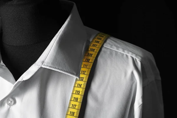 Mannequin with custom tailored shirt and measuring tape on dark background, closeup — 스톡 사진