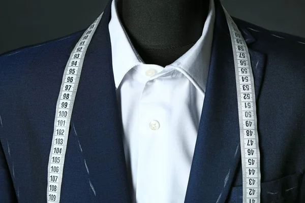 Tailor's mannequin with unfinished clothes and measuring tape on dark background, closeup — 스톡 사진