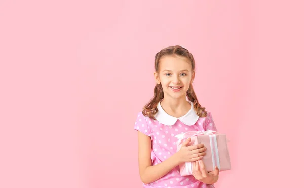 Söt liten flicka med gåva på färg bakgrund — Stockfoto