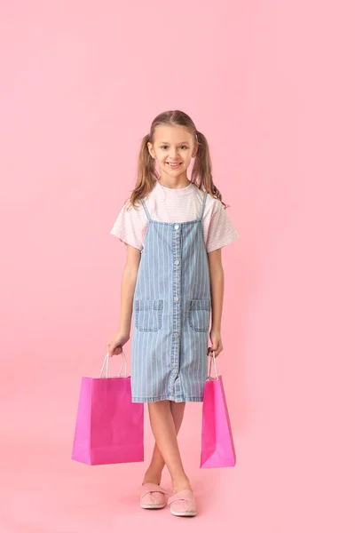 Linda niña con bolsas de compras en el fondo de color — Foto de Stock