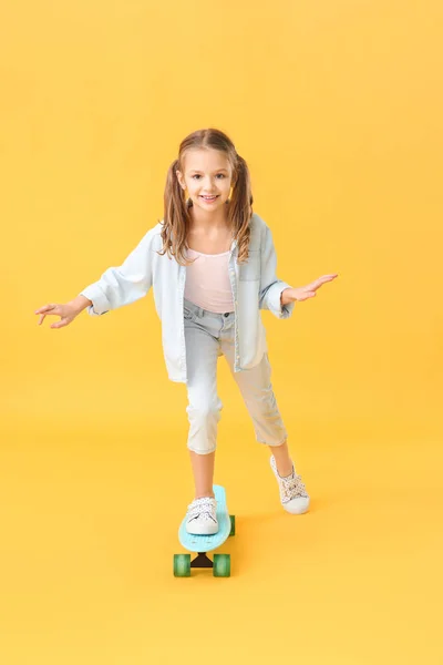 Petite fille mignonne avec planche à roulettes sur fond de couleur — Photo