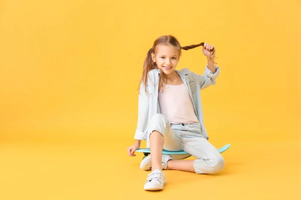 Cute little girl with skateboard on color background — Stock Photo, Image