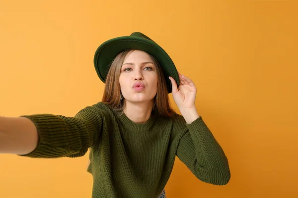 Mooie jonge vrouw het nemen van selfie op kleur achtergrond — Stockfoto