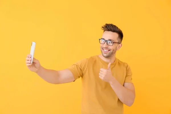 Handsome man taking selfie on color background — Stock Photo, Image