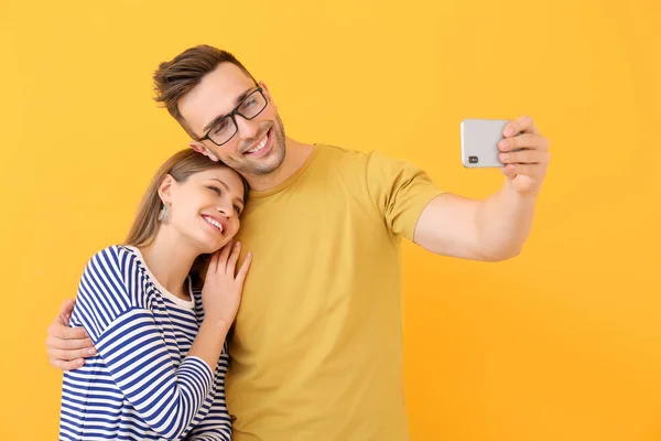 Pareja joven tomando selfie sobre fondo de color — Foto de Stock